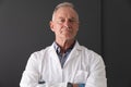 Portrait of caucasian senior male doctor wearing white coat standing with arms crossed, smiling Royalty Free Stock Photo