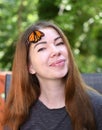 Portrait of a caucasian smiling woman with the butterfly on her face in the garden Royalty Free Stock Photo