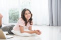 Portrait of Caucasian teenage girl in casual clothes smiling, lying on floor at home while using laptop Royalty Free Stock Photo