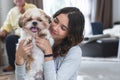 Portrait of Caucasian teenage girl playing with shih tzu puppy dog at home. Young beautiful woman sitting on floor, smiling, Royalty Free Stock Photo