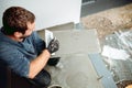 Portrait of caucasian tiler placing ceramic wall tile in position over adhesive with lash tile levelling system. Royalty Free Stock Photo