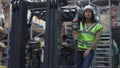 Portrait of Caucasian woman in hard hat standing on forklift as autoloader operator driving machinery in slow motion