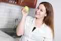 Portrait of Caucasian woman holding hand a green tasty apple, domestic kitchen Royalty Free Stock Photo