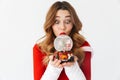 Portrait of caucasian woman 20s wearing Santa Claus red costume smiling and holding Christmas snow ball, isolated over white Royalty Free Stock Photo