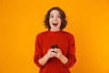 Portrait of caucasian woman holding and using cell phone while standing isolated over yellow background Royalty Free Stock Photo