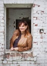 Portrait of a Caucasian Woman Wearing a Tan Leather Jacket Leaning Out the Window of an Old Brick Building