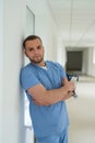Portrait of caucasian young male doctor in blue uniform stant on hospital corridor Royalty Free Stock Photo