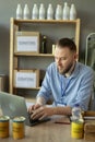 Portrait of Caucasian young man charity center worker sitting in warehouse typing on laptop. Royalty Free Stock Photo