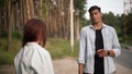 Portrait of Caucasian young man talking with angry woman arguing with partner outdoors. Handsome boyfriend hitchhiking