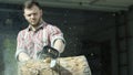 Portrait of caucasian young man worker sawing a log with a chainsaw. Video. Male carpenter sawing a part of tree trunk Royalty Free Stock Photo