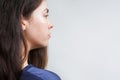 Portrait of a Caucasian young woman with long dark hair, in profile. Grey background and copy space. The concept of beauty and