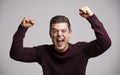 Portrait of a celebrating young white man with arms up