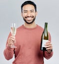 Portrait, champagne and cheers with a man in studio on a gray background holding a bottle for celebration. Glass