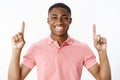 Portrait of charismatic good-looking pleasant and happy young african american guy lifting hands pointing up and smiling