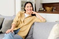 Portrait of charming asian woman with brunette hair. Smiling female sitting on the couch and looking at the camera