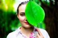 Portrait charming beautiful woman. Attractive woman holds a green leaf close her half face. Gorgeous girl compare her face and le