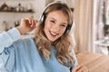 Portrait of charming blond girl 20s wearing headphones listening to music at home Royalty Free Stock Photo