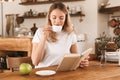 Portrait of charming blond woman reading book and drinking coffee while sitting in cozy cafe indoor Royalty Free Stock Photo