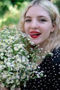 portrait of a charming blonde teenage girl wearing teeth braces with bouquet of white wildflowers. female with braces in Royalty Free Stock Photo