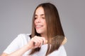 Portrait of charming brunette hair lady combing hair with hairbrush comb, isolated. Young beautiful woman brush long Royalty Free Stock Photo