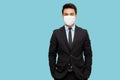Portrait of a charming businessman dressed in suit wearing protective medical mask and looking at Royalty Free Stock Photo