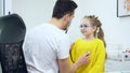 Portrait of charming Caucasian girl inhaling and exhaling as doctor using stethoscope. Cute little patient visiting