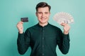 Portrait of charming cheerful handsome guy hold credit card presenting cash fan on teal background Royalty Free Stock Photo