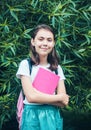 Portrait of a charming child holding a notebook, smiling in a white t-shirt with a backpack on his back, standing in the open air Royalty Free Stock Photo