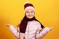 Portrait of a charming cute little girl in a jacket, scarf and hat on a yellow background. Autumn and winter concept Royalty Free Stock Photo