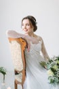 Portrait of a charming dark-haired bride sitting on the chair and holding bouquet of flowers, Studio, close-up. Wedding Royalty Free Stock Photo
