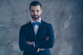 Portrait of charming guy crossing his hands looking wearing modern classy bow tie blazer jacket over grey