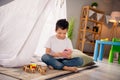 Portrait of charming happy small boy sitting floor hold gadget device wear white shirt stylish child room interior Royalty Free Stock Photo