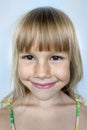 Portrait of a charming little girl 7 years old. A wide smile on his face, a dark tan, blond hair. On a gray background. Royalty Free Stock Photo