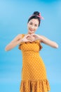Portrait of charming millennial showing her feelings care making heart with fingers wearing polka dot skirt dress isolated over