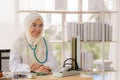 Portrait of charming muslim female doctor working at office desk and smiling at camera