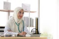 Portrait of charming muslim female doctor working at office desk and smiling Royalty Free Stock Photo