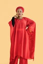Portrait of charming pleasant African woman wearing red traditional red suit and turban, looking at camera isolated on
