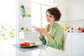 Portrait of charming positive lady sit chair kitchen table hold smart phone make picture homemade lunch plate house