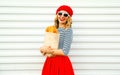 Portrait charming smiling woman wearing french red beret holding paper bag with long white bread baguette on white