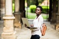 Time for study. Portrait of charming smiling young woman with laptop device in hands smiling at camera at campus. Cheerful afro am