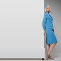 Portrait of charming stewardess wearing in blue uniform. Empty billboard