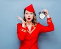 Vintage stewardess wearing in red uniform with alarm clock