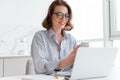 Portrait of charming woman in glasses and striped shirt using mo