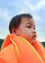 3 years old Asian little girl with orange life jacket looking up to the sky Royalty Free Stock Photo