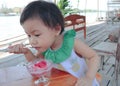 Asian girl eating strawberry ice cream on wooden table Royalty Free Stock Photo