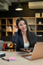 Charming young-adult asian businesswoman sitting in the office with her tablet and laptop Royalty Free Stock Photo