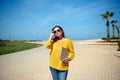 Beautiful young adult woman in sunglasses, standing with a laptop in her hand and looking confidently at camera Royalty Free Stock Photo