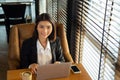 Portrait charming young Asian woman in formal suit sitting in front of laptop coffee cup and smart phone on wooden table, looking Royalty Free Stock Photo