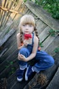 Portrait of a charming young girl with a rose at an old log house. Close-up of a blue-eyed blonde teen Royalty Free Stock Photo