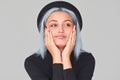 Portrait of charming young teenager woman with blue hair wearing black apparel and hat, smiling, looking up. Cute positive female Royalty Free Stock Photo